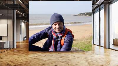 man handsome on sea beach in warm clothing winter woolen hat Wall mural