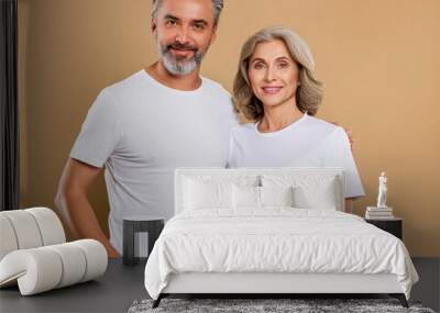 Old middle age couple with blank mockup white t-shirt standing lovely man and woman front brown light background Wall mural