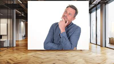 Pensive young bearded man in blue shirt looking up aside copy space posing isolated on white background studio portrait Wall mural