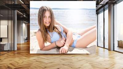 Portrait of smiling girl lying on sand beach summer Wall mural