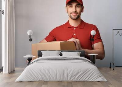 Young handsome man bearded courier holding brown cardboard box shipping logistic job Wall mural