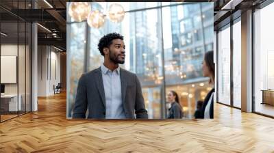 A confident man in formal attire walks through a glass atrium, symbolizing ambition, aspiration, and the fast-paced rhythm of corporate life in a stylish environment. Wall mural