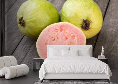 Two guavas with sliced fruit over wooden table Wall mural