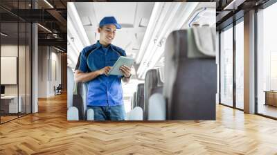 a male bus crew member using a digital tablet while standing on the bus Wall mural