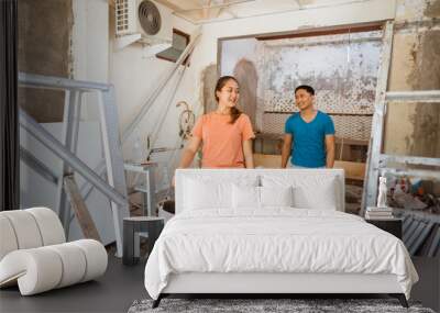 a young couple walking with buckets of cement to renovate a room Wall mural