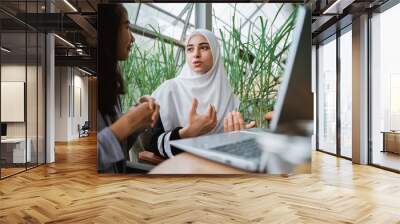 arab muslim woman explain while meeting with friend in cafe Wall mural