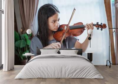 beautiful girl playing violin with violin bow indoors at home Wall mural