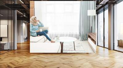 beautiful housewife wearing hijab watching television in a leisu Wall mural