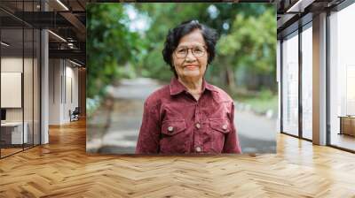 close up confident Asian grandma wearing eyes glasses stand in the park Wall mural