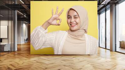 close up young hijab women happy and show the OK sign isolated on a yellow background Wall mural