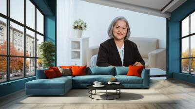 Confident senior business woman when sitting on the work desk Wall mural