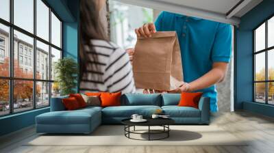 Delivery man delivering food to a woman at home. online food shopping service concept Wall mural