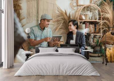 designer man and woman entrepreneur talk about selling handicrafts using tablet and laptop computer on a background of various handicrafts Wall mural