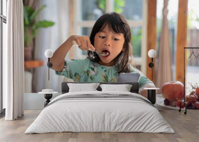 distracted kid using mobile phone while having breakfast on the table Wall mural