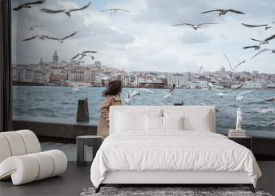 excited little girl looking at seagulls flying around her while going to bosphorus turkey Wall mural