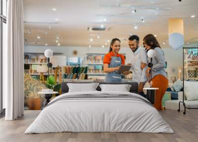 female shop assistant serving a husband and wife customer with a tablet at a furniture store Wall mural