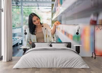 female shopkeeper holding the digital tablet while observing the liquid stock at the store shelf Wall mural