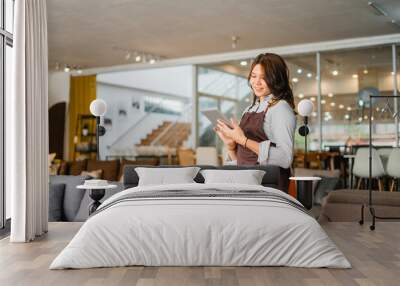 female waitress in apron using a tab standing in front of couch in furniture store department Wall mural