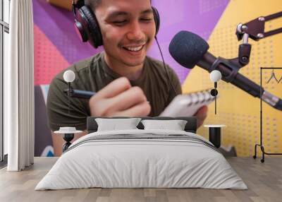 happy asian man is recording a podcast in his studio take note Wall mural