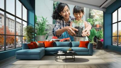 happy excited mother and her daughter gardening together plants some flower at home Wall mural