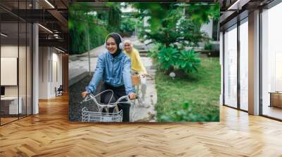 indonesian veiled women with headphones on bicycle on bike path lane in the park Wall mural