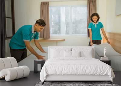 male and female cleaners wearing uniforms making beds in hotel rooms Wall mural