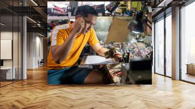 male technician observing the circuit while working at the workbench in the service station Wall mural