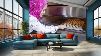 middle aged asian woman with hijab making semperit cake. woman baking industry Wall mural