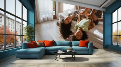 mother and little girl lying on the bed having fun together Wall mural