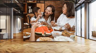 mother feeding her boy son during family gathering at home Wall mural