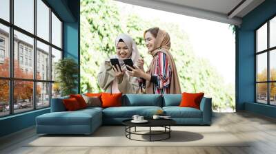 muslim woman in head scarf meet friends and using phone in the park Wall mural