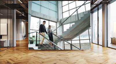 partner of business walking down with chatting on stairs in the office building Wall mural