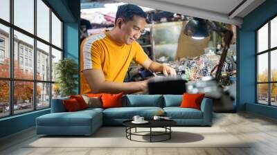 portrait of an Asian electrical repairman sitting at a work table in a workshop Wall mural