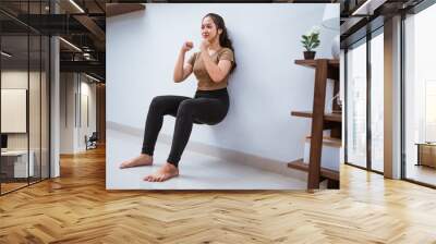 portrait of young asian woman squating against the wall at home Wall mural