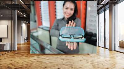 selective focus of glasses in eyeglass box with copyspace against the background of a beautiful woman smiling in an optician Wall mural