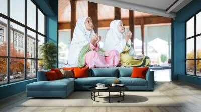 two Asian Muslim girls together sitting on the floor worship and prays for Allah in the mosque Wall mural