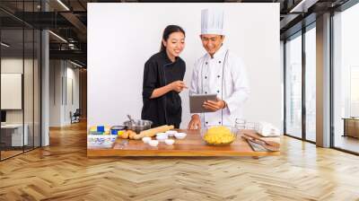 two chefs using a pad before processing food ingredients on a table on isolated background Wall mural