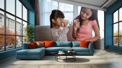 two kid sibling sister having a glass of water to drink at home Wall mural