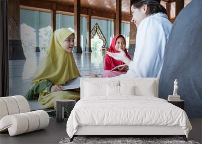 two kids learning to read quran with muslim teacher or ustad in mosque Wall mural