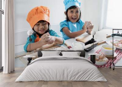 two little asian girl toddler learn cooking and make some dough together and wearing apron in the kithcen Wall mural