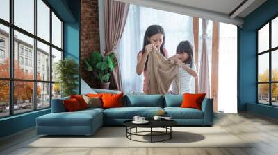 two sisters closed his nose by his finger when holding a smell clothes when doing household chores together Wall mural