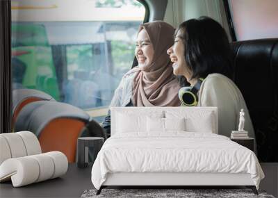 two young women laugh while chatting together while sitting on the bus Wall mural