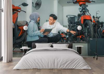 veiled female shop assistant serves a motorcycle buyer while holding a tablet Wall mural