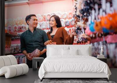 young Asian couple choosing accessories while shopping at an accessories store in the mall Wall mural