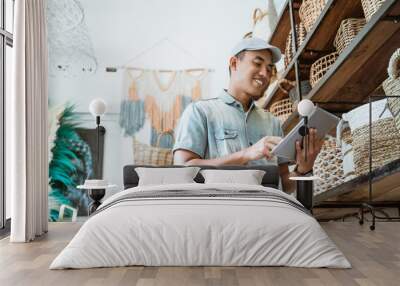 young entrepreneur smiles while holding a digital tablet while standing in a craft shop Wall mural