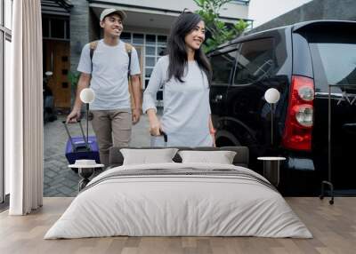 young happy couple getting ready to go on holiday vacation. put suitcases in to the car trunk Wall mural