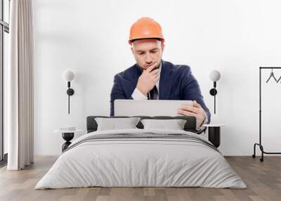 A tired constructor businessman in an orange helmet looks at the laptop screen and studies the construction project. Sits at the table and drinks coffee, nervous Wall mural