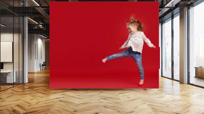 Happy childhood. Funny child girl jumping and having fun isolated on red background. Celebrating a vibrant carnival for kids, birthday party. True emotions. Space for text Wall mural