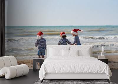 Happy Little children travelers in Santa hats having fun on tropical beach. Christmas and new year holiday vacation concept.  Wall mural