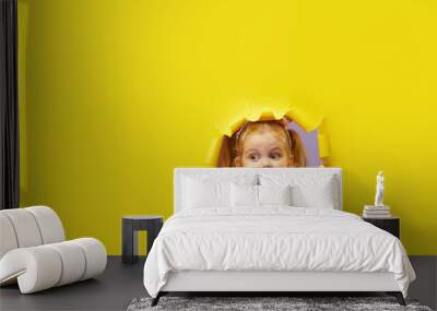 Little child looking, peeping through the bright yellow paper hole. Advertise children's goods. Wow and shocked funny face. Happy childhood concept. Copy space for text Wall mural